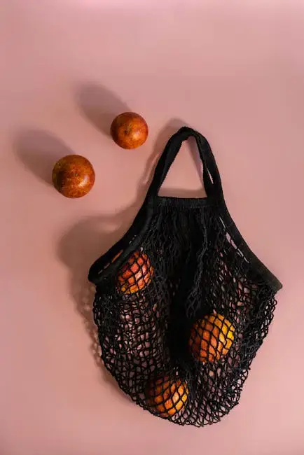 Mesh bag with oranges on pink background.